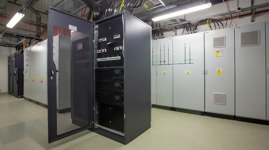 Redundancy challenges in Tier III/IV-aligned colocation data centers - Two redundant UPS systems connected to a shared control panel, illustrating how common control logic can synchronize failures.